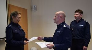 Komendant wręcza list gratulacyjny policjantce odchodzącej na emeryturę.