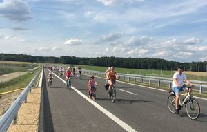 Odcinek drogi ekspresowej S11. Na nim jadący dorośli rowerzyści oraz dzieci na małych rowerkach.