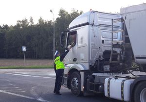 Olesno ulica Gorzowska. Policjant ruchu drogowego podaje kierowcy samochodu ciężarowego urządzenie pomiarowe do badania stanu trzeźwości.