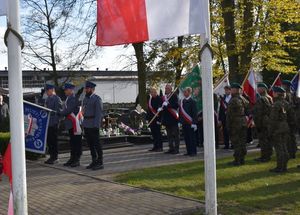 Poczet Sztandarowy Oleskiej Policji występuje przed pomnik. W tle zgromadzeni.