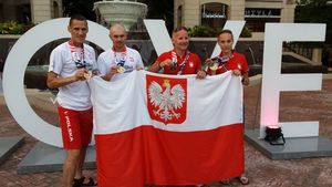 Reprezentanci polskiej Policji prezentują zdobyte medale podczas igrzysk w Adelajdzie. Przed sobą trzymają biało-czerwoną flagę.