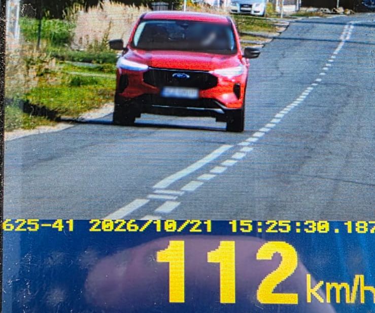 Zdjecie przedstawia czerwony pojazd na jezdni pod spodem zółte cyfry 112 km/h