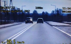 Widok z policyjnej kamery wideorejestratora. Jezdnia, pasy ruchu rozdzielone podwójną linia ciągłą, dwa samochody podczas manewru mijania. W lewym dolnym narożniku wyświetlona prędkość 101,5 km/h.