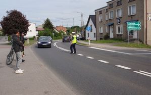 Policjant drogówki zatrzymuję wstrzymuje ruch samochodów tarczą sygnałową.