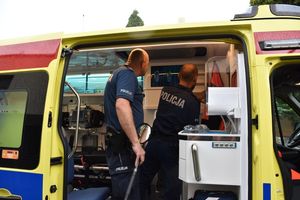 dwóch policjantów sprawdza wnętrze ambulansu, zaglądają do półek we wnętrzu pojazdu.