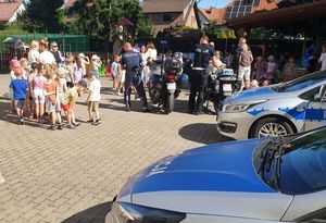 Plac przy szkole podstawowej nr 3. Policjanci prezentują dzieciom radiowozy i motocykle. Przy nich gromadka dzieci.