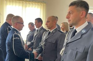 Pierwszy Zastępca Komendanta Wojewódzkiego Policji w Opolu inspektor Krzysztof Buchała gratuluje awansu jednemu ze stojących w szeregu policjantów.