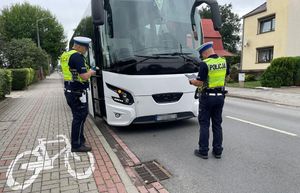 Ulica Krasickiego w Oleśnie, okolica Domu Harcerza. Dwóch policjantów ruchu drogowego sprawdza autokar przed wyjazdem.