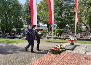 Cmentarz komunalny w Oleśnie. Przedstawiciele Policji i Państwowej Straży Pożarnej składają wiązankę kwiatów przed pomnikiem Lotników Polskich.