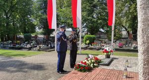 Cmentarz komunalny w Oleśnie. Przedstawiciele Policji i Państwowej Straży Pożarnej oddają honor przed pomnikiem Lotników Polskich.