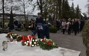 Komendant Powiatowy Policji w towarzystwie Komendanta Państwowej Straży Pożarnej składa wieniec na pomniku Lotników Polskich. W tle uczestnicy uroczystości.