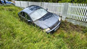 Ulica Kluczborska w Wojciechowie. W przydrożnym rowie stoi ciemny samochód osobowy. Widać uszkodzony betonowy płot posesji. W tle prawy policyjnego radiowozu policjantów ruchu drogowego.