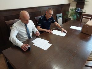 Zdjęcie w kolorze przedstawia jak Komendant Powiatowy Policji w Oleśnie i Burmistrz 
Olesna podpisują dokumenty.