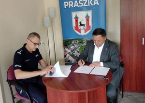 Zdjęcie w kolorze przedstawia jak Komendant Powiatowy Policji w Oleśnie i Burmistrz 
Miasta i Gminy Praszka podpisują dokumenty.