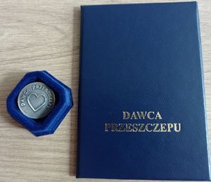 Zdjęcie w kolorze przedstawia niebieską legitymację i medal w etui z napisem &quot;Dawca Szpiku&quot;