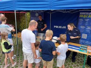 Zdjęcie w kolorze przedstawia kilka osób odwiedzających stoisko policyjne.