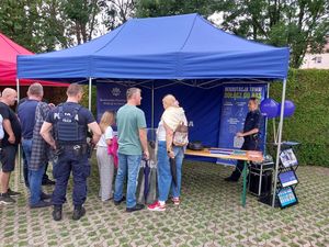 Zdjęcie w kolorze przedstawia kilka osób odwiedzających stoisko policyjne.