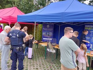 Zdjęcie w kolorze przedstawia kilka osób odwiedzających stoisko policyjne.