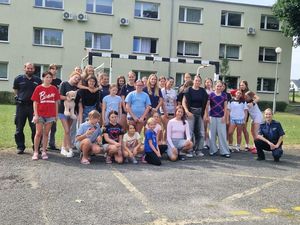 Zdjęcie w kolorze, przedstawia dziewczęta pozujące w grupie do zdjęcia wspólnie z policjantem.