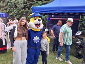 Zdjęcie w kolorze przedstawia młoda kobietę i dziewczynkę pozujące z maskotka Opolskiej Policji do zdjęcia.