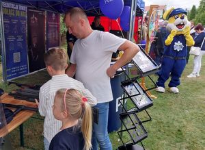 Zdjęcie w kolorze przedstawia uczestników imprezy odwiedzających policyjne stoisko promocyjne.