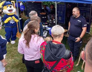 Zdjęcie w kolorze przedstawia uczestników imprezy odwiedzających policyjne stoisko promocyjne.