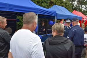 Zdjęcie w kolorze przedstawia uczestników imprezy odwiedzających policyjne stoisko promocyjne.