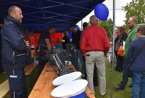 Zdjęcie w kolorze przedstawia uczestników imprezy odwiedzających policyjne stoisko promocyjne.