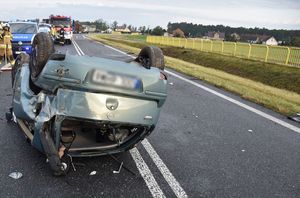 Zdjęcie w kolorze przedstawia rozbity pojazd obrócony kołami do góry na jezdni.