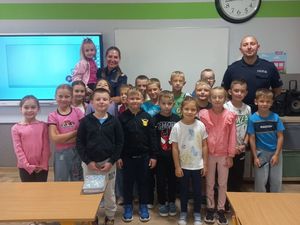 Zdjęcie w kolorze przedstawia uczniów pozujących do zdjęcia w klasie z policjantami.