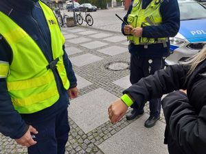 Zdjęcie w kolorze przedstawia jak policjanci wręczają kobiecie odblask.