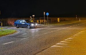 Zdjęcie w kolorze przedstawia policjanta stojacego przy pojeździe zatrzymanym na jezdni.