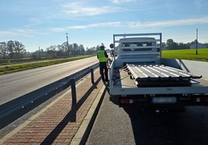 Zdjęcie w kolorze przedstawia, policjanta podczas kontroli pojazdu - lawety.