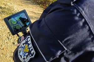 Zdjecie w kolorze przedstawia, lewe ramię operatora drona który trzyma w dłoniach pilot z ekranem.