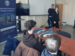 Zdjęcie w kolorze przedstawia młodzież podczas prelekcji z policjantem ruchu drogowego.