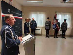 Zdjęcie w kolorze przedstawia nowego Komendanta Powiatowego Policji podczas przemówienia w tle Poczet Sztandarowy KPP w Oleśnie