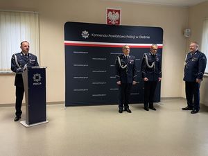 Zdjęcie w kolorze przedstawia nowego Komendanta Powiatowego Policji podczas przemówienia w tle ścianka z płótna z napisem KPP w Oleśnie