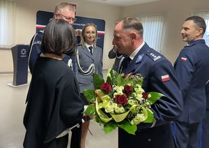 Zdjęcie w kolorze przedstawia nowego KPP w Oleśnie podczas wręczania mu kwiatów przez pracowników cywilnych i policjantów.