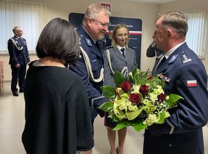 Zdjęcie w kolorze przedstawia Nowego KPP w Oleśnie podczas wręczania mu kwiatów przez pracowników cywilnych i policjantów.