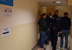 Zdjęcie w kolorze przedstawia policjanta oraz pracowników cywilnych w korytarzu KPP w Oleśnie.