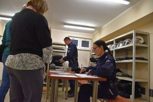 Zdjęcie w kolorze przedstawia magazyn uzbrojenia policjantów obsługujących poszczególne punkty wydawania wyposażenia dla pracowników cywilnych.