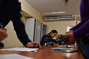 Zdjęcie w kolorze przedstawia magazyn uzbrojenia na pierwszym planie kobiece dłonie trzymają karabin AKMS.