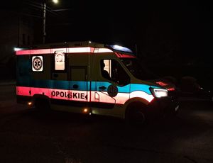 Zdjęcie w kolorze przedstawia oświetloną od środka karetkę pogotowia medycznego, do koła panuje mrok.