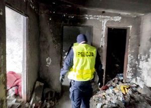 Zdjęcie w kolorze przedstawia policjanta w kamizelce odblaskowej w pustostanie.