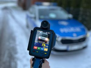 Zdjęcie w kolorze przedstawia miernik prędkości z wyświetloną prędkością 78 km/h i zdjęciem pojazdu. W tle zaparkowany pojazd policji.