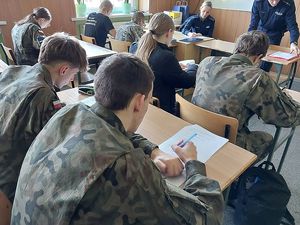 Zdjęcie w kolorze przedstawia uczniów klas mundurowych rozwiązujących test wiedzy.