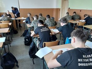 Zdjęcie w kolorze przedstawia uczniów klas mundurowych rozwiązujących test wiedzy.
