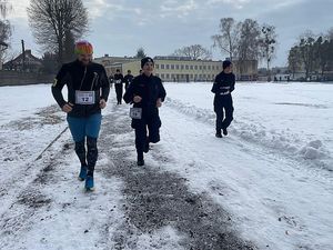 Zdjęcie przedstawia policjantki biegnące po zaśnieżonej bieżni.