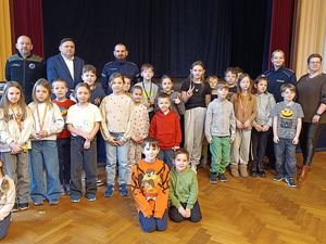 Zdjęcie w kolorze przedstawia, uczestników półkolonii pozujących do wspólnego zdjęcia z policjantami i przedstawicielami instytucji.