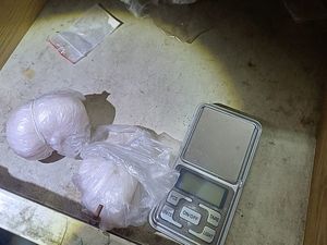 Zdjęcie w kolorze, przedstawia wnętrze szuflady, gdzie leży worek foliowy z białą substancją, obok niego znajduje się waga jubilerska.